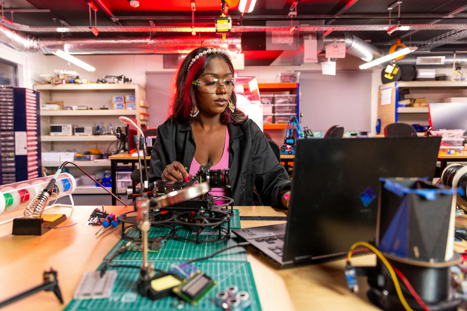 young woman fixing a camera and looking at a laptop