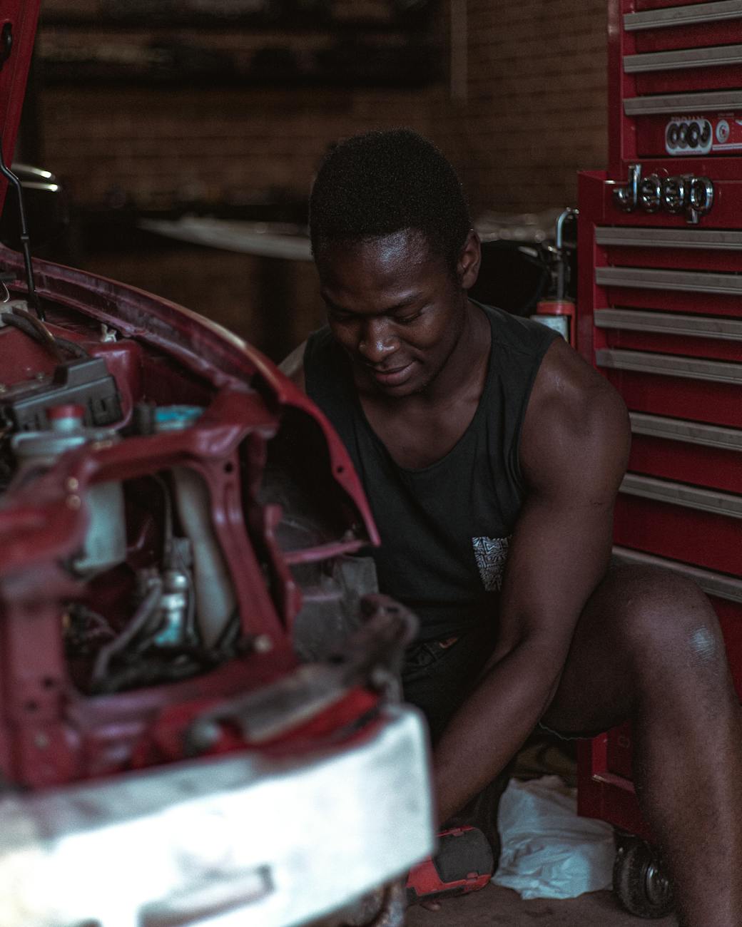 concentrated ethnic repairman fixing car in workshop